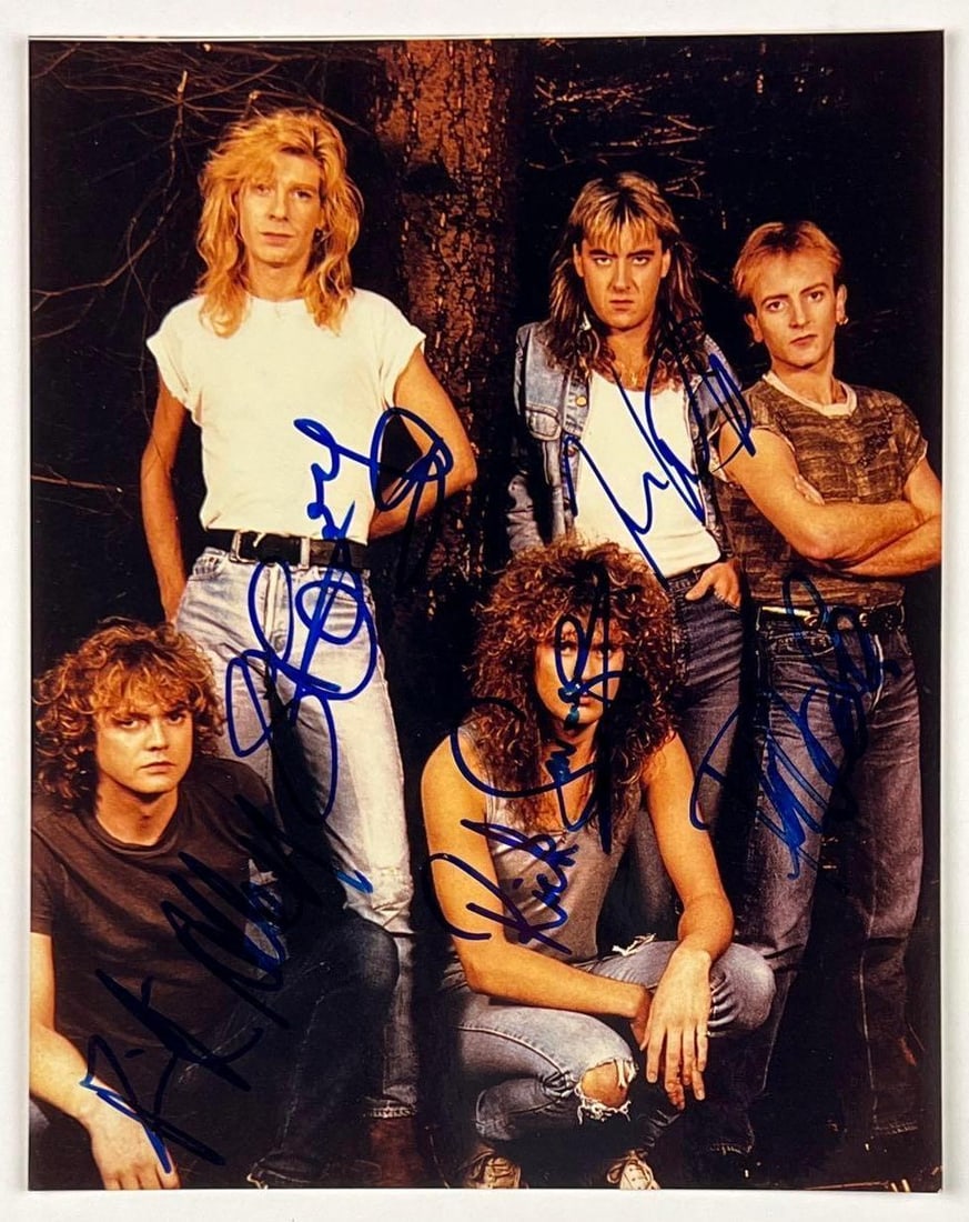 Def Leppard Fully Group Signed 10" x 8" Photo (5 Sigs) (Beckett/BAS Authentication): Color 10" x 8" photo signed in blue felt tip marker by Def Leppard band members Steve Clark, Rick Allen, Joe Elliott, Phil Collen, and Rick Savage. In fine condition. Obtained in-person. Accompanied