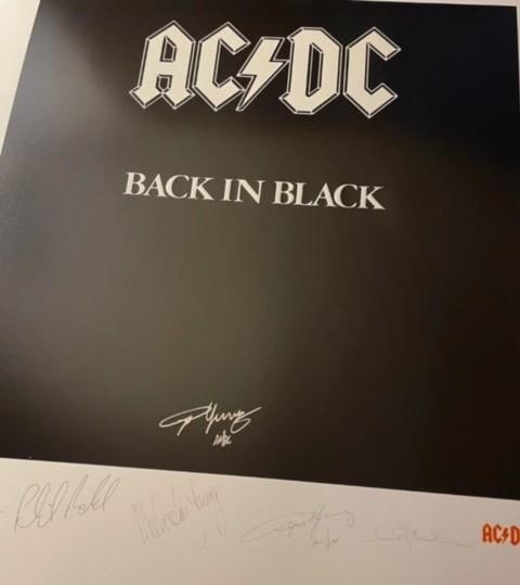 AC/DC: Angus Young Signed 26" x 22" "Back in Black" Lithograph (Third Party Guaranteed): Black-and-white 26" x 22" lithograph signed in silver felt tip marker by AC/DC band member Angus Young, who also added the band name "AC/DC" after his name. Litho features band signatures pre-printed