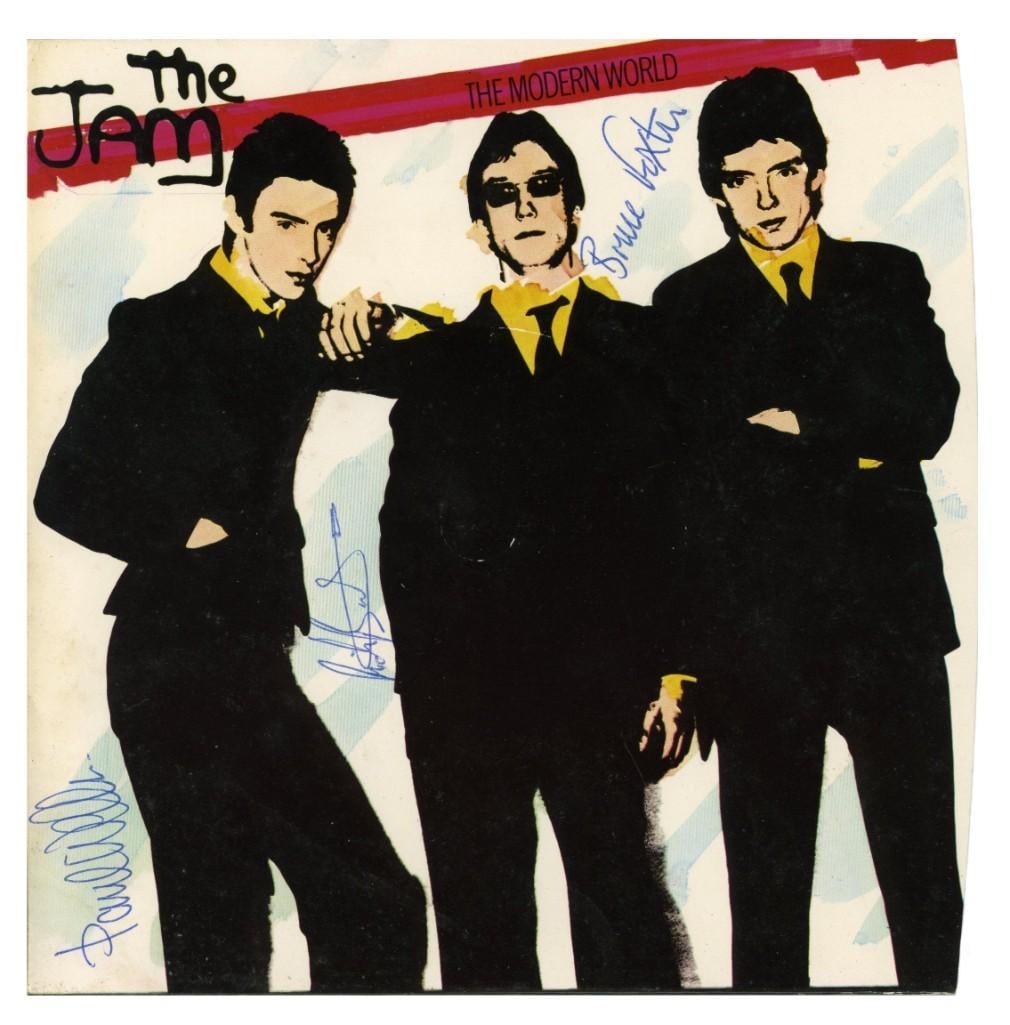 The Jam Fully Group Signed "The Modern World" 45 Single (3 Sigs) (Tracks Authentication): "The Modern World" 45 UK vinyl pressing single signed on the cover in blue ballpoint pen by The Jam band members Paul Weller, Bruce Foxton, and Rick Bucker. Measuring approximately 7" x 7" and in
