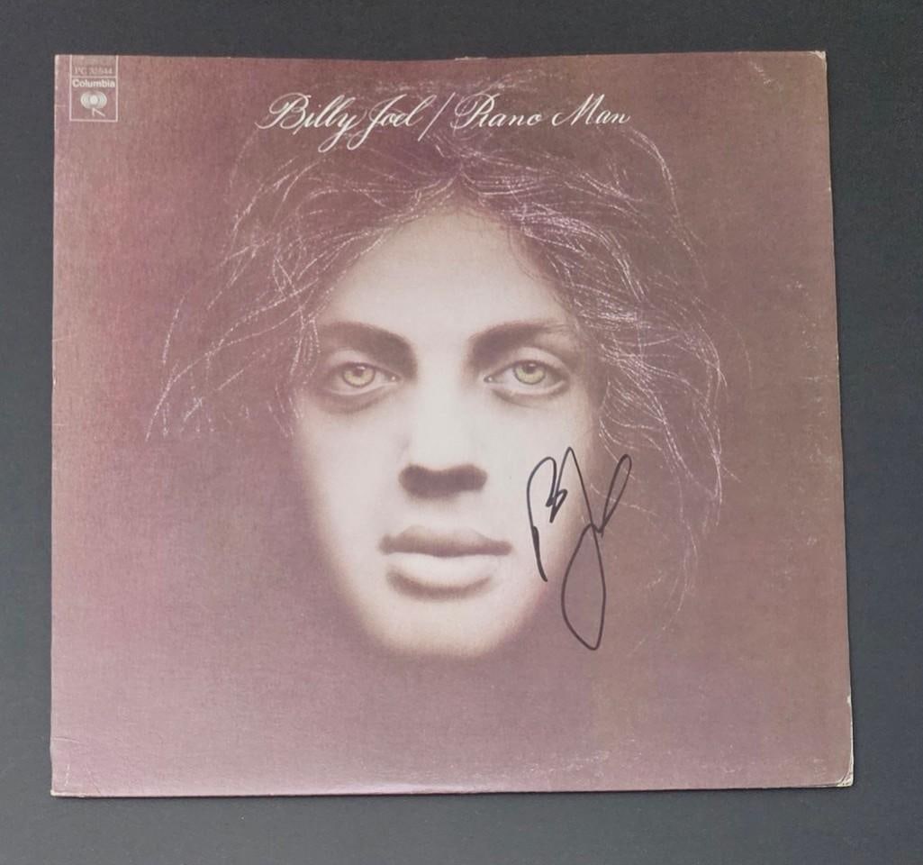 Billy Joel Signed "Piano Man" Album (Third Party Guaranteed): "Piano Man" album signed on the cover in black felt tip marker by musician Billy Joel. Measuring approximately 12" x 12" and in fine condition. Record is included. Obtained in-person.ProvenanceEaton