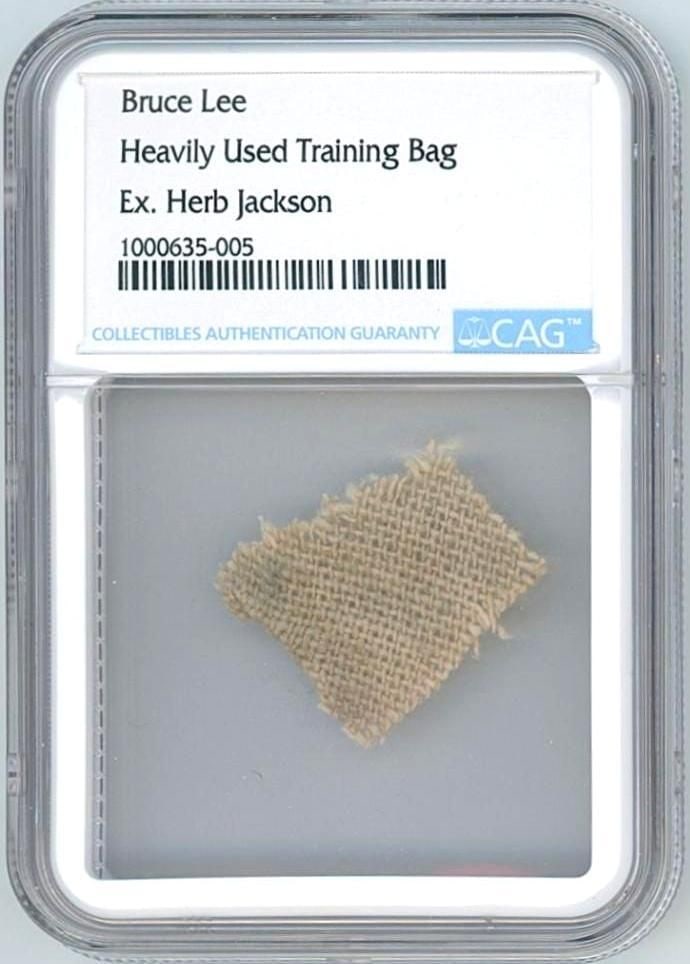 Bruce Lee Swatch from Personally Used Jeet Kune Do Training Bag (CAG Encapsulated): Square canvas swatch, approximately 1" x .75," from a heavily used Jeet Kune Do training bag personally owned by Bruce Lee. The fabric shows expected soiling from use and is encapsulated by CAG to a s