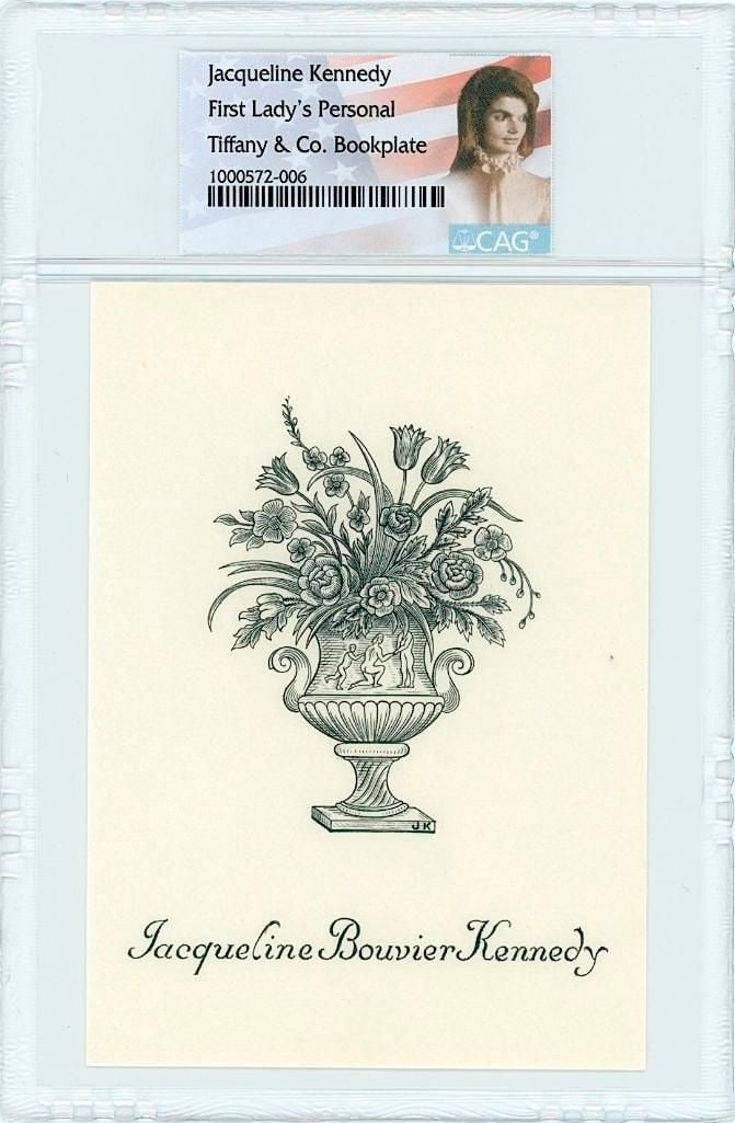 Jacqueline Kennedy Personal Bookplate (CAG Encapsulated): Original Tiffany & Co. bookplate from the personal library of Jacqueline Kennedy, measuring 2.75" x 4". Features a floral urn motif with “Jacqueline Bouvier Kennedy” printed below.