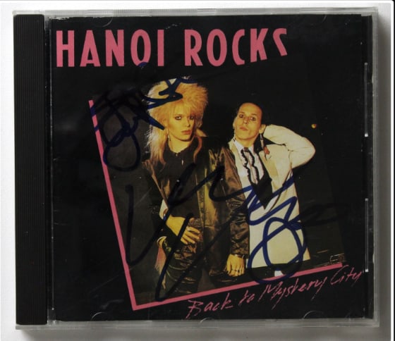 Hanoi Rocks: Michael Monroe & Sam Yaffa Signed “Back to Mystery City” CD (Beckett): "Back to Mystery City” CD signed on the cover in blue felt tip marker by Hanoi Rocks band members Michael Monroe and Sam Yaffa. Measuring approximately 5” x 5” and in fine