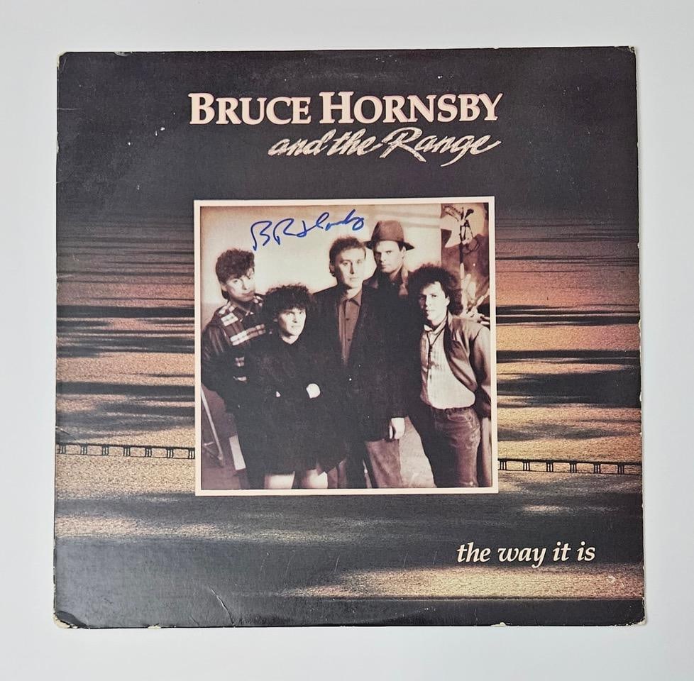 Bruce Hornsby Signed "The Way It Is" Album (Third Party Guaranteed): "The Way It Is" album signed on the cover in blue felt tip marker by musician Bruce Hornsby. Measuring approximately 12" x 12" and in fine condition. Provenance Eaton & Brennan Auctions guarantees thi