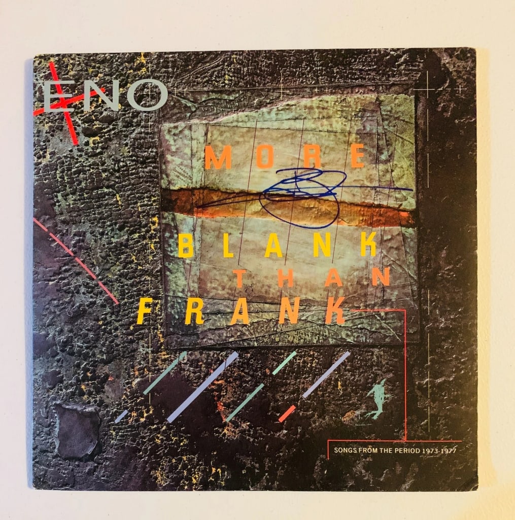 Brian Eno Signed "More Blank Than Frank" LP Album (Beckett/BAS Authentication): "More Blank Than Frank" LP album signed on the cover in blue felt tip marker by musician Brian Eno. Measuring approximately 12" x 12" and in fine condition. Obtained in-person. Record is included. Aut