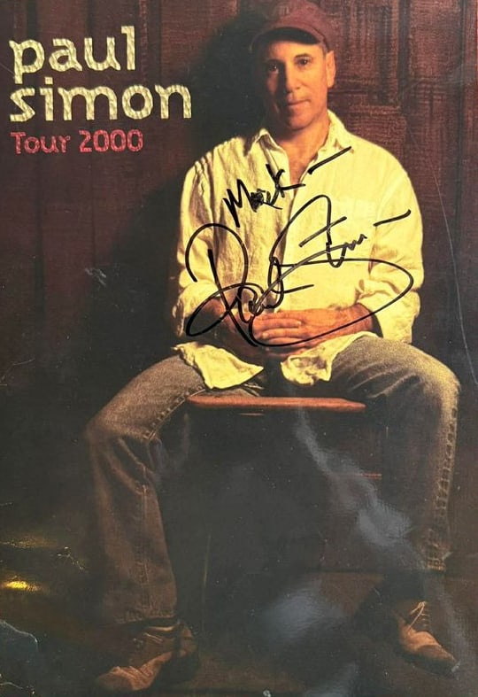 Paul Simon Signed "Tour 2000" Tour Book (ACOA Authentication): Color "Tour 2000" tour book signed in black felt tip marker by musician Paul Simon, who also inscribed "Mark--" before his signature. In very good condition, with some scattered wear, and bit of brush