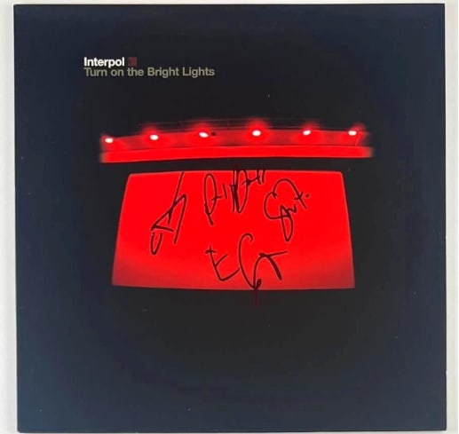 Interpol Group Signed "Turn on the Bright Lights" Album (4 Sigs) (JSA Authentication): "Turn on the Bright Lights" album signed on the cover in black felt tip marker by Interpol band members Paul Banks, Daniel Kessler, Carlos Dengler, and Sam Fogarino. Measuring approximately 12" x 12"