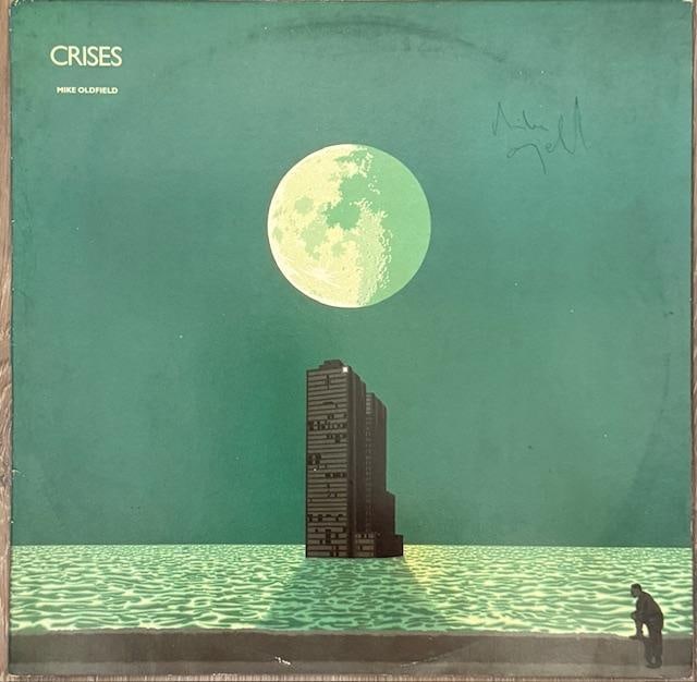 Mike Oldfield Signed "Crisis" LP Album (TPG): "Crisis" LP album signed on the cover in blue ballpoint pen by musician Mike Oldfield. Measuring approximately 12" x 12" and in very good condition, with some signs of scattered wear. Record is includ