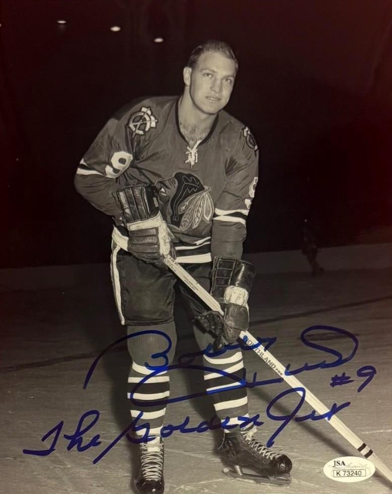 Bobby Hull Signed 10" x 8" Photo (JSA): Black-and-white 10" x 8" photo signed in blue felt tip marker by hockey player Bobby Hull, who also signed his jersey number "#9" and his nickname "The Golden Jet" after his signature. In fine
