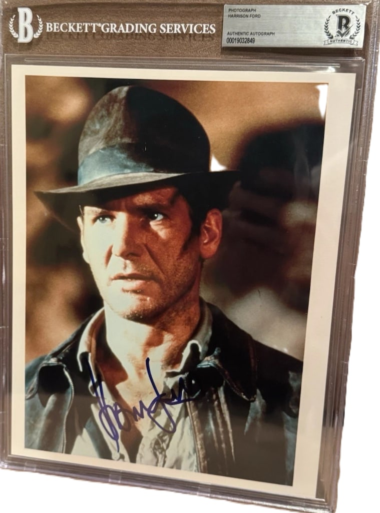 Harrison Ford Signed Slabbed "Raiders of the Lost Ark" 10" x 8" Photo as Indiana Jones (Beckett): Color slabbed 10" x 8" photo of character Indiana Jones from the film "Raiders of the Lost Ark" signed in blue felt tip marker by actor Harrison Ford. In fine condition. Encapsulated and