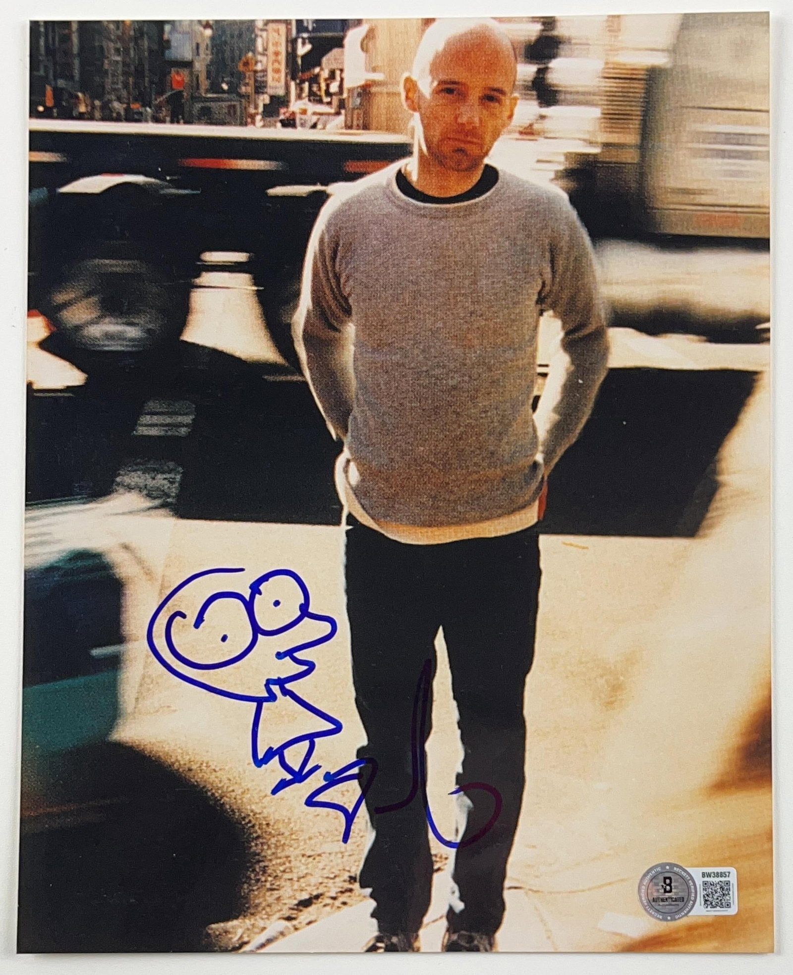 Moby Signed 10" x 8" Photo (Beckett Authentication): Color 10" x 8" photo signed in blue felt tip marker by musician Moby, who also included a doodle of himself before his signature. In fine condition. Authenticated by Beckett, with their official