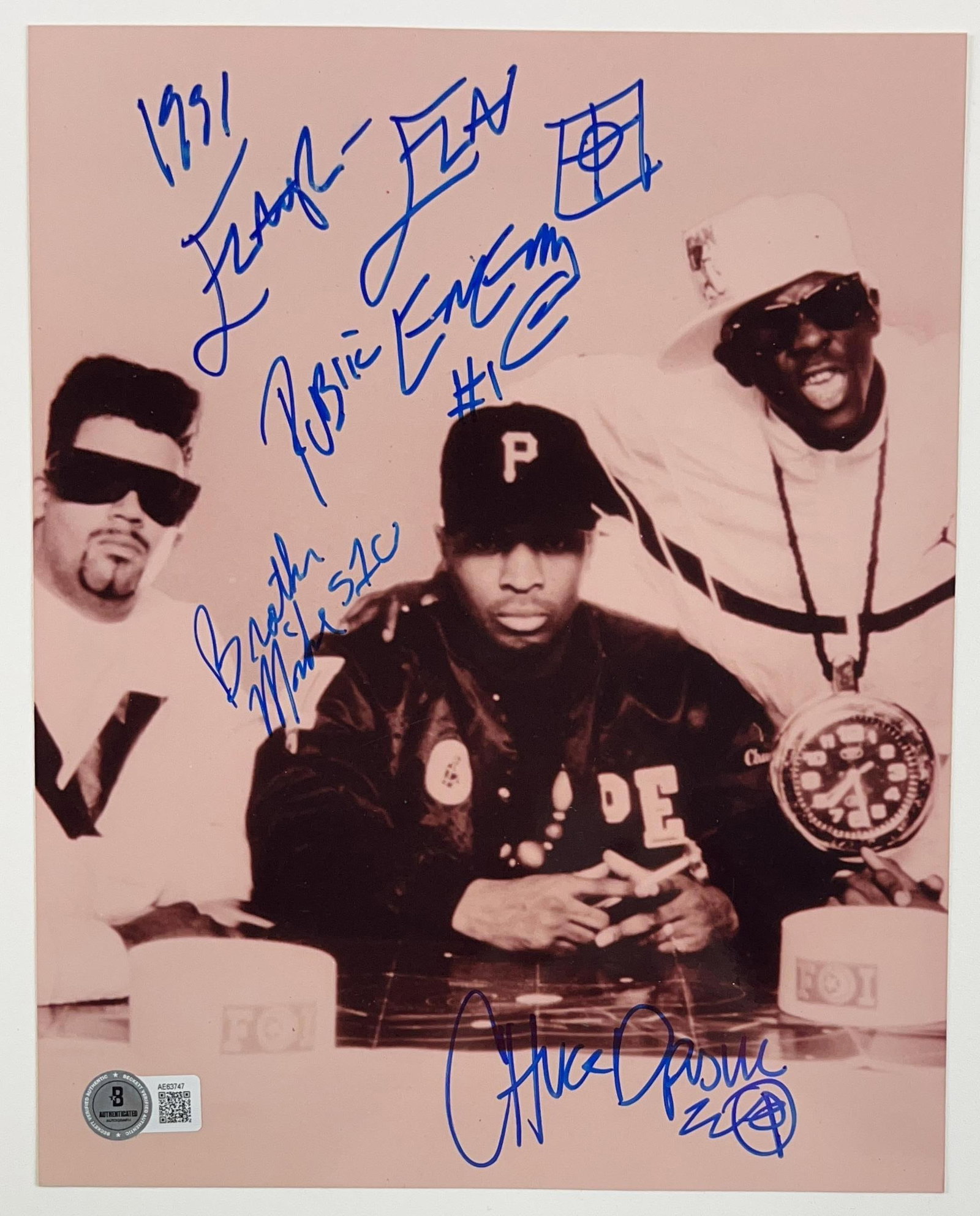 Public Enemy Group Signed 10" x 8" Photo (3 Sigs) (Beckett Authentication): Black-and-white 10" x 8" photo signed in blue felt tip marker by Public Enemy band members Chuck D, Flavor Flav, who inscribed the date "1991" before his signature, and the band name "Public Enemy