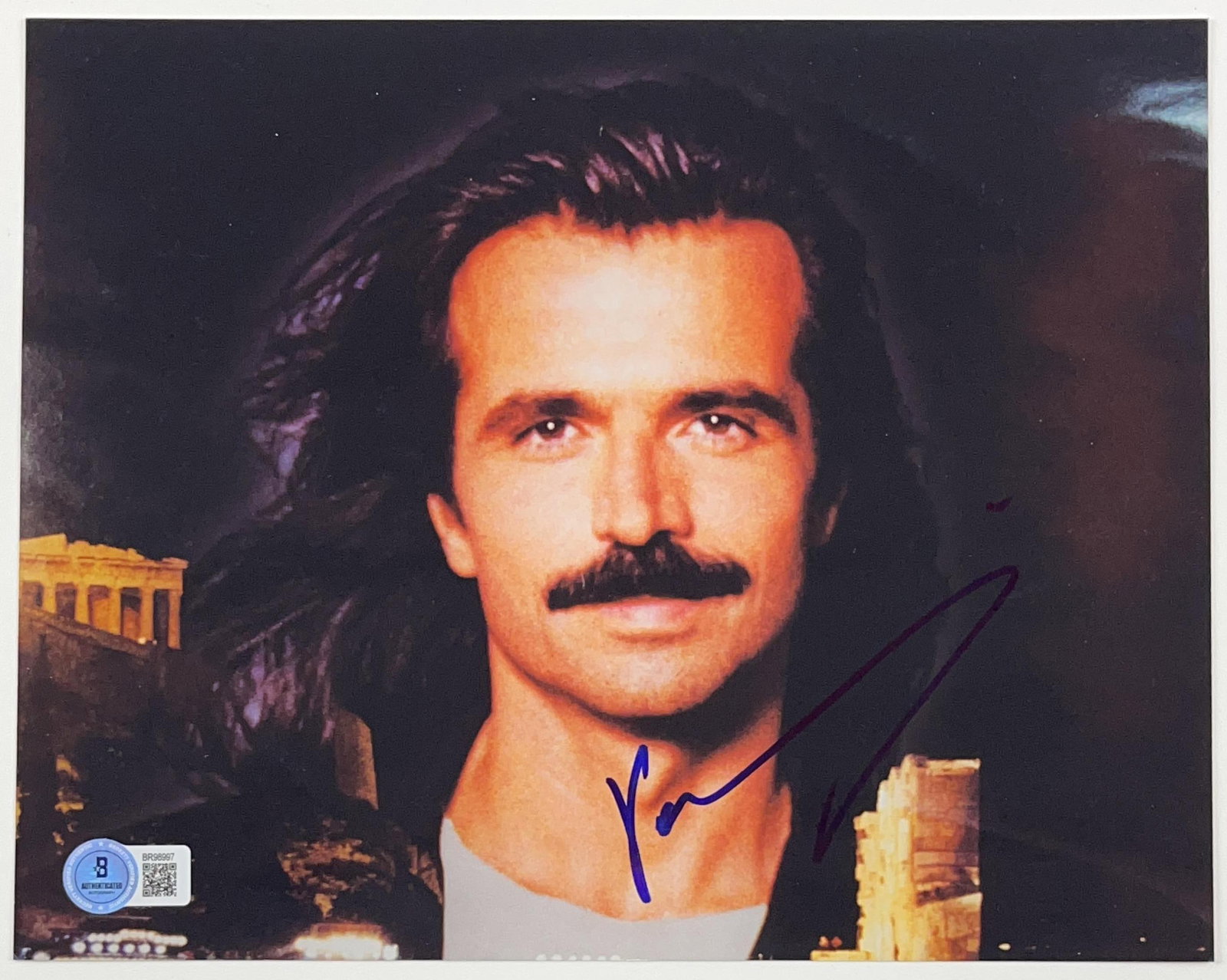 Yanni Signed 8" x 10" Photo (Beckett Authentication): Color 8" x 10" photo signed in blue felt tip marker by musician Yanni. In fine condition. Authenticated by Beckett, with their official hologram affixed to the front bottom left corner (#BR98997)-