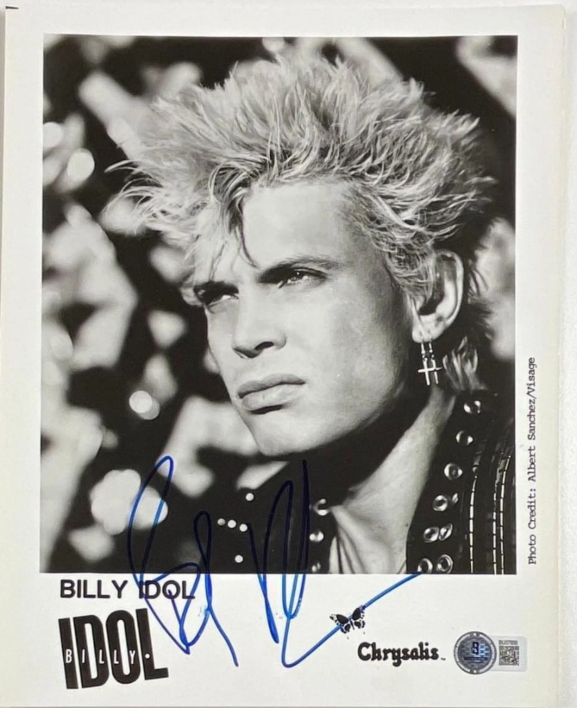Bill Idol Signed 10" x 8" Promo Photo (Beckett Authentication): Black-and-white 10" x 8" promotional photo signed in blue felt tip marker by musician Billy Idol. In fine condition. Authenticated by Beckett, with their official hologram affixed to the front bottom