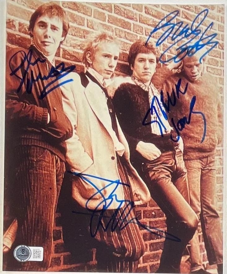 Sex Pistols Group Signed 10" x 8" Photo (3 Sigs) (Beckett Authentication): Color 10" x 8" photo signed in blue felt tip marker by Sex Pistols band members Johnny Rotten, Glenn Matlock, Paul Cook, and Steve Jones. In fine condition. Obtained in-person. Accompanied by a full L