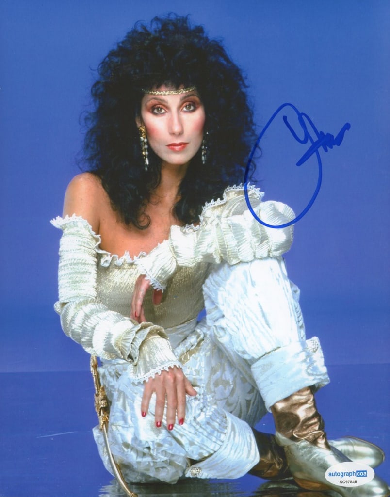 Cher Signed 10" x 8" Photo (ACOA Authentication): Color 10" x 8" photo signed in blue felt tip marker by musician Cher. In fine condition. Accompanied by an ACOA COA (#SC97846). Obtained in-person.