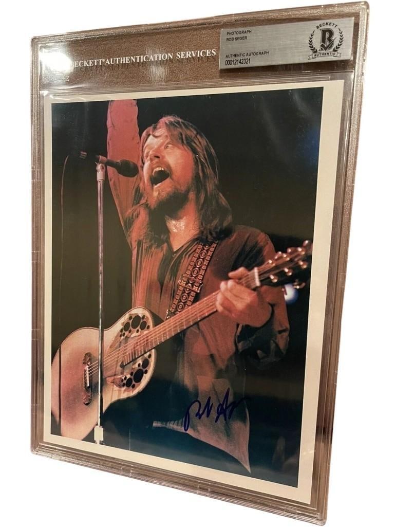 Bob Seger Signed 10" x 8" Photo (Beckett Encapsulated): Color encapsulated 10" x 8" photo signed in blue felt tip marker by musician Bob Seger. In fine condition. Encapsulated and authenticated by Beckett (#00012142321). An often reluctant signer, Bob