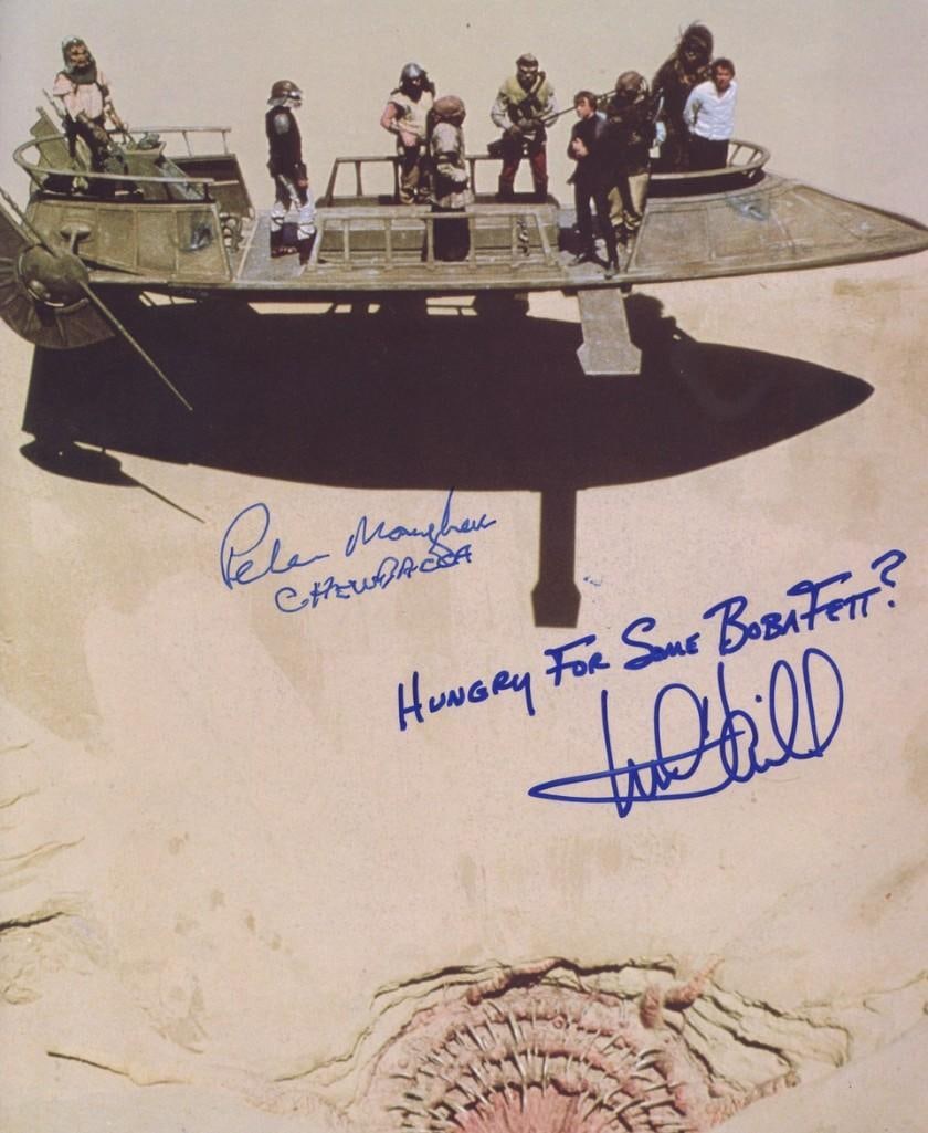 Star Wars: Mark Hamill & Peter Mayhew Signed 10" x 8" Photo (2 Sigs) (Third Party Guaranteed): Color 10" x 8" photo of multiple characters on a desert skiff from the film "Star Wars: Return of the Jedi," signed in blue felt tip marker by actors Mark Hamill and Peter Mayhew. Mayhew also signed h