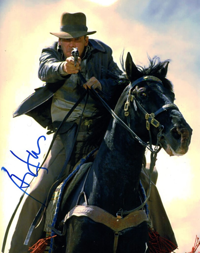 Indiana Jones: Harrison Ford Signed 14" x 11" Photo (JSA Authentication): Color 14" x 11" photo of the character Indiana Jones from the film "Indiana Jones" signed in blue felt tip marker by actor Harrison Ford. In fine condition. Accompanied by a full Letter of