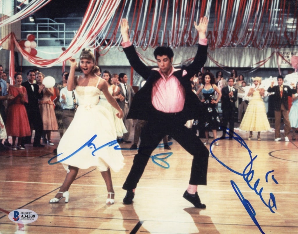 Grease: Olivia Newton John & John Travolta Signed 8" x 10" Photo (2 Sigs) (Beckett): Color 8" x 10" photo from Grease signed in blue felt tip marker by actors Olivia Newton John and John Travolta. In fine condition. Accompanied by a full Letter of Authenticity from Beckett/BAS (#A3433