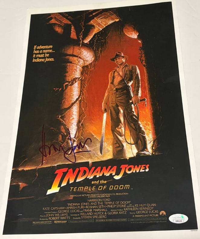 Indiana Jones & the Temple of Doom: Harrison Ford Signed 17" x 11" Mini-Poster (JSA Authentication): Color 17" x 11" mini poster from the film "Indiana Jones & the Temple of Doom" signed in blue felt tip marker by actor Harrison Ford. In fine condition. Authenticated by JSA, with their official holog