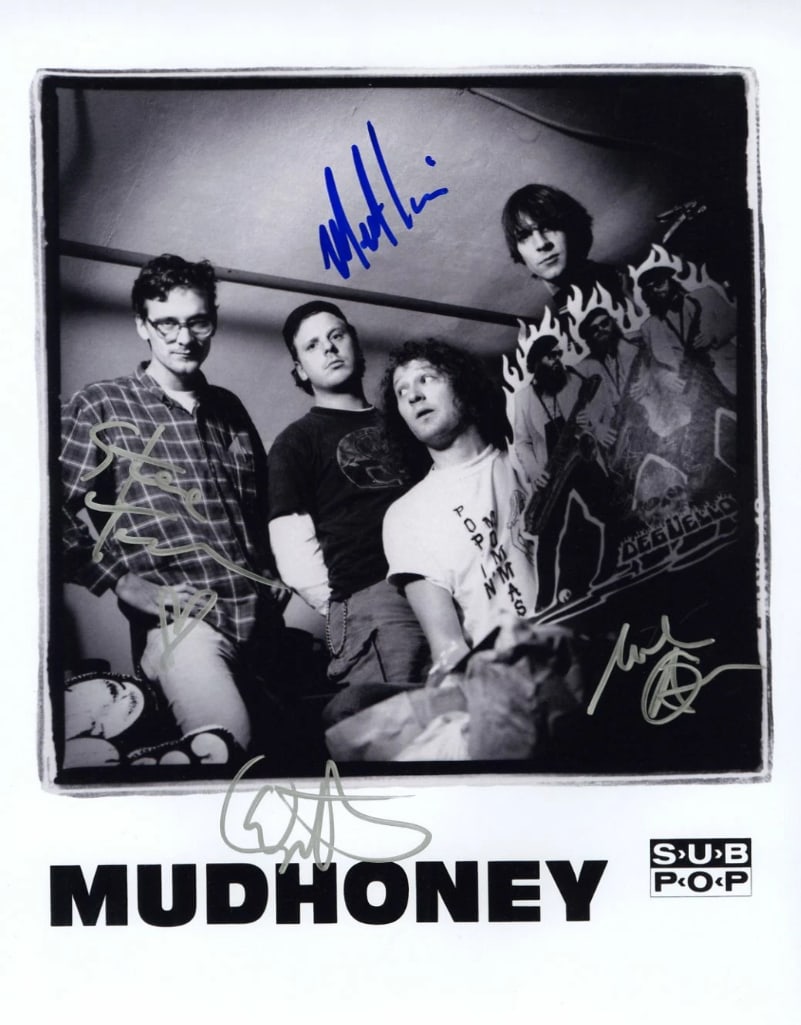 Mudhoney Group Signed 14" x 11" Promo Photo (4 Sigs) (ACOA Authentication): Black-and-white 14" x 11" promotional photo signed in blue and silver felt tip markers by Mudhoney band members Mark Arm, Steve Turner, Guy Maddison, and Dan Peters. In fine condition. Accompanied by 