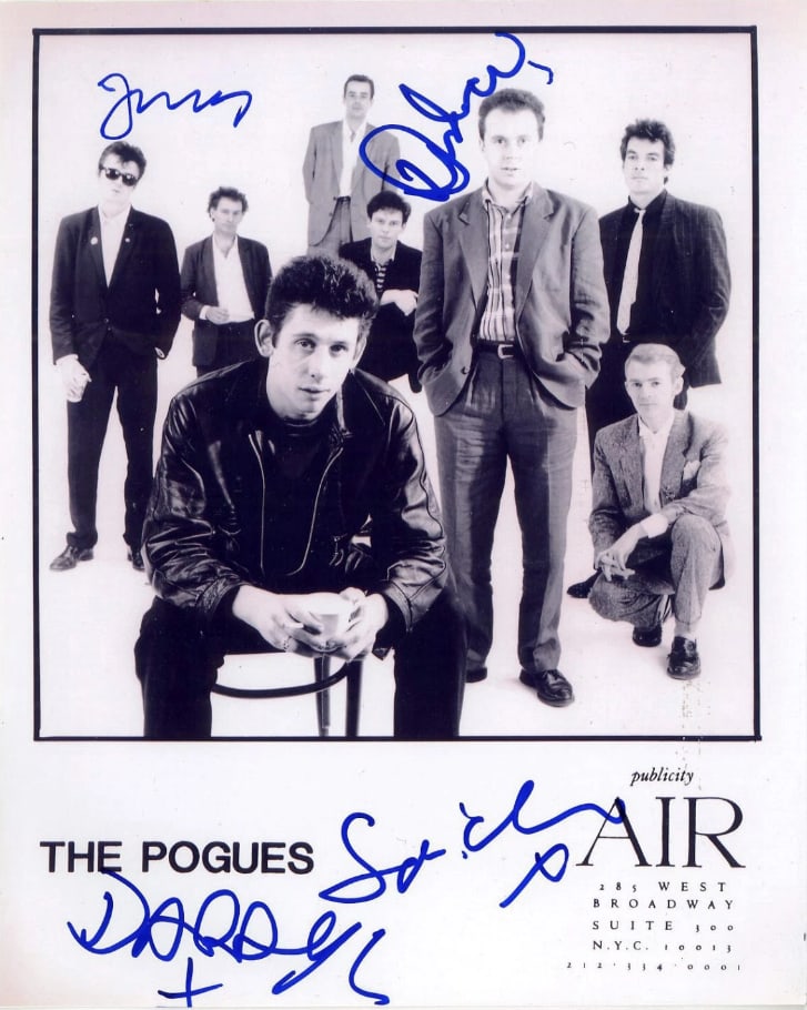 The Pogues Group Signed 10" x 8" Promo Photo (4 Sigs) (ACOA): Black-and-white 10" x 8" promotional photo signed in blue felt tip marker by The Pogues band members Spider Stacy, James Fearnley, Andrew Ranken, and Darryl Hunt. In fine condition. Accompanied by an 