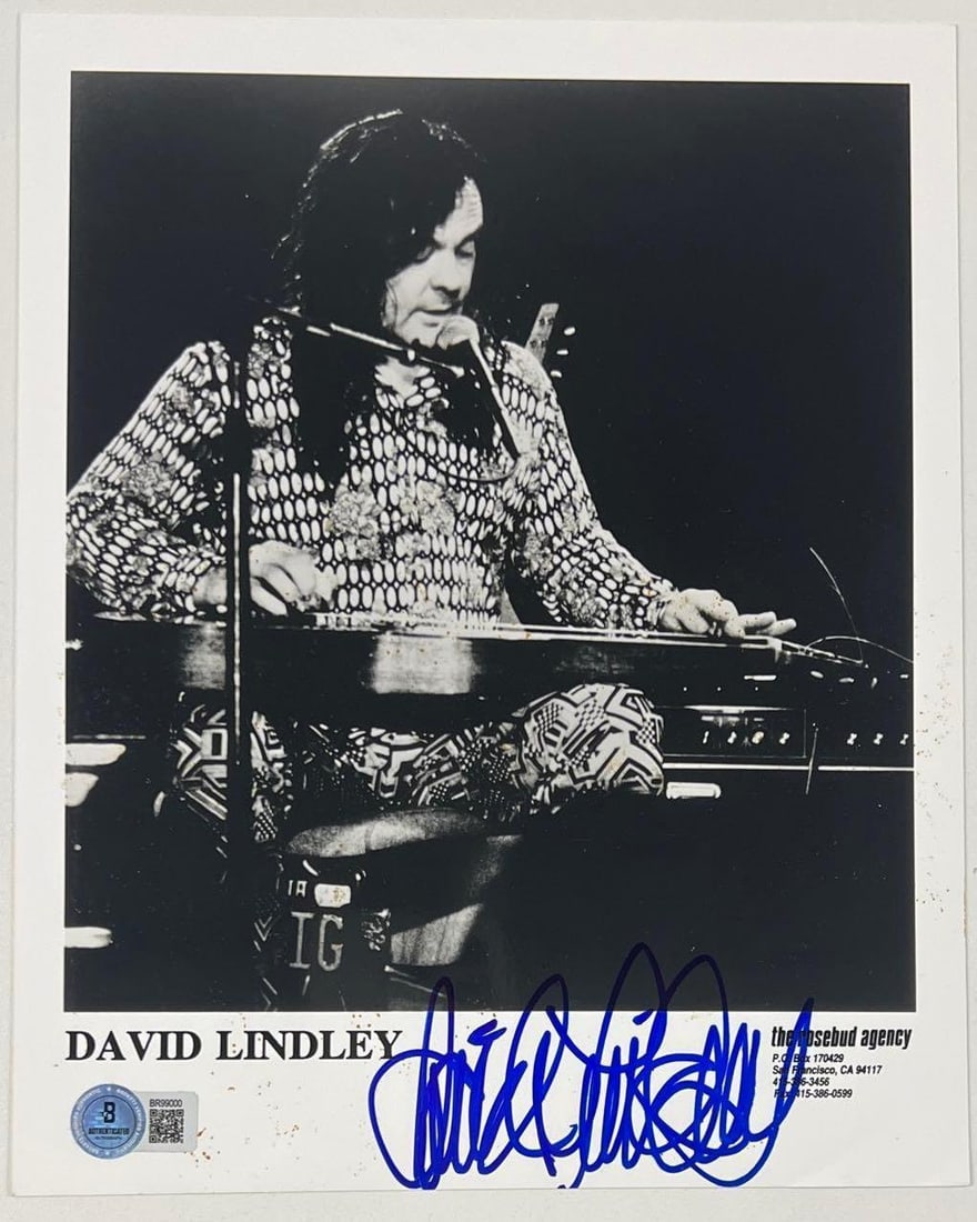 David Lindley Signed 10" x 8" Press Photo (Beckett Authentication): Black-and-white 10" x 8" press photo signed in blue felt tip marker by musician David Lindley. In fine condition. Authenticated by Beckett, with their official hologram affixed to the front bottom lef