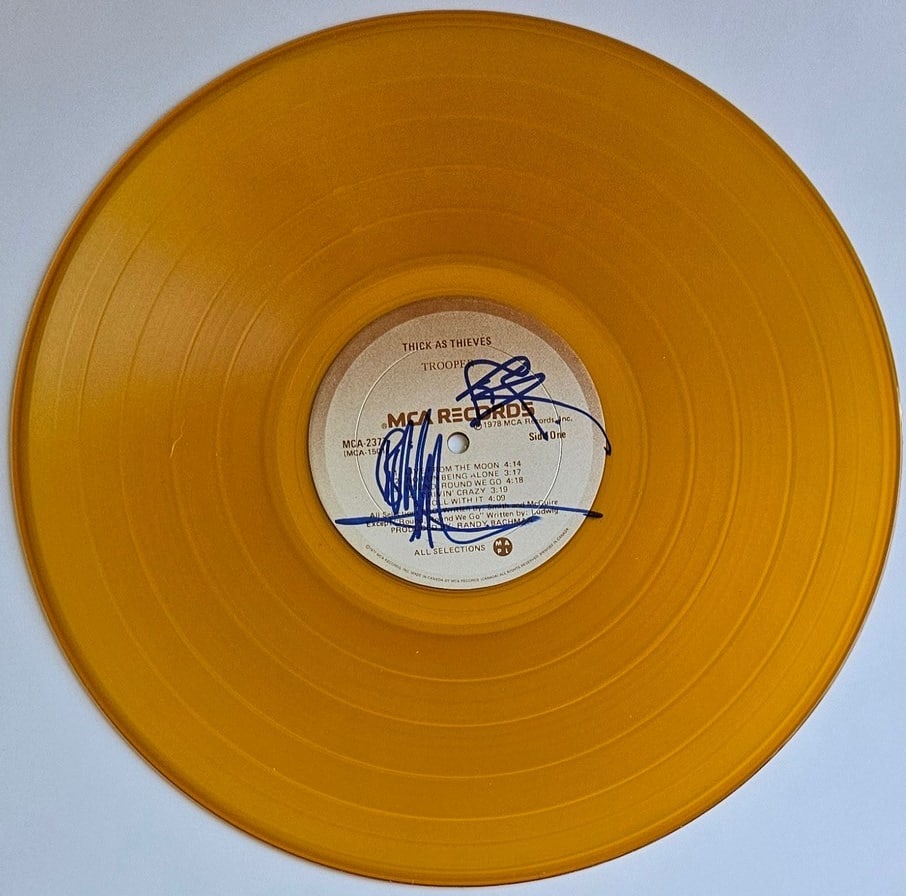Trooper: Ra McGuire & Brian Smith Signed "Thick as Thieves" Vinyl Disc (2 Sigs): "Thick as Thieves" vinyl disc signed on the front in blue felt tip marker by Trooper band members Ra McGuire and Brian Smith. Measuring approximately 12" x 12" and in fine condition. Provenance Eaton