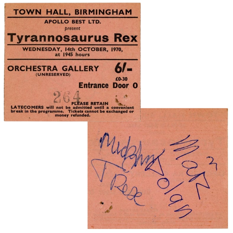 T.Rex: Marc Bolan & Mickey Finn Signed 1970 Ticket Stub (2 Sigs) (Tracks COA): Rare light pink 2.5" x 3" ticket stub signed on the reverse in blue ballpoint pen by T. Rex members Marc Bolan and Mickey Finn. In very good condition, with one small pin hole to the bottom left