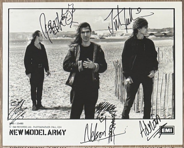 New Model Army Fully Signed 8 x 10 Promo Photo (4 Sigs) (Third Party Guaranteed): Black-and-white 8 x 10 promotional photo signed in black felt tip marker by New Model Army band members Justin Sullivan, Ed Alleyne-Johnson, Robert Heaton, who drew a stick figure of himself, Adrian P