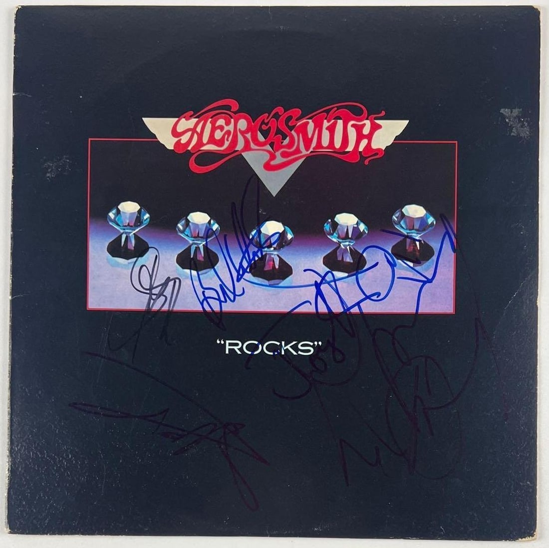 Aerosmith Fully Group Signed "Rocks" Album (5 Sigs) (Beckett Authentication): "Rocks" album signed on the cover in blue felt tip marker by Aerosmith band members Steven Tyler, Joe Perry, Brad Whitford, Joey Kramer, and Tom Hamilton. Measuring approximately 12" x 12" and in fine