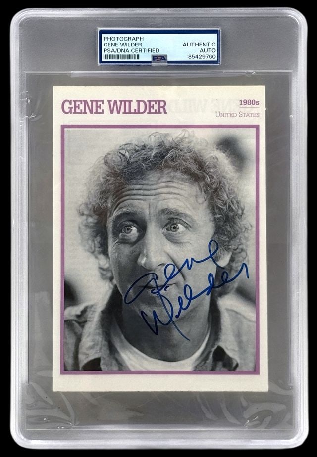 Gene Wilder Signed 7" x 4.75" Biographical Career Card (PSA/DNA Encapsulated): Black-and-white 7" x 4.75" biographical career card signed on the front portrait side in blue felt tip marker by actor Gene Wilder. In fine condition. Encapsulated and authenticated by PSA/DNA