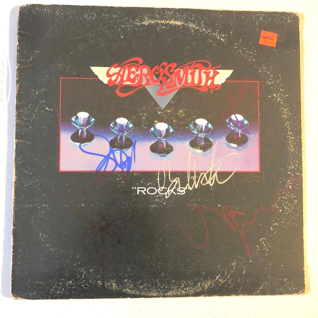 Aerosmith Fully Group Signed "Rocks" Album (5 Sigs) (Beckett Authentication): "Rocks" album signed on the cover in blue and silver felt tip markers by Aerosmith band members Steven Tyler, Joe Perry, Tom Hamilton, Brad Whitford, and Joey Kramer. Measuring approximately 12" x