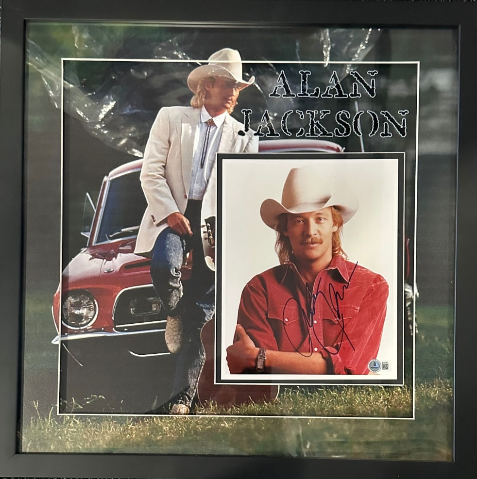 Alan Jackson Signed 10” x 8” Photo Framed (Beckett Authentication): Color 10” x 8" photo signed in blue felt tip marker by musician Alan Jackson. Photo is displayed in a frame measuring 22" x 22" overall. In fine condition. Beckett authentication hologram