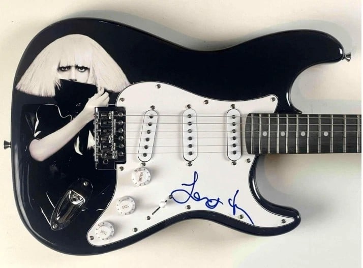 Lady Gaga Signed Custom “The Fame Monster” Graphics Fender-Style Guitar (JSA Authenticat: "The Fame Monster" custom graphics Fender-style guitar signed on the pickguard in blue felt tip marker by musician Lady Gaga. Measuring approximately 39" x 13" and in fine condition. Obtained