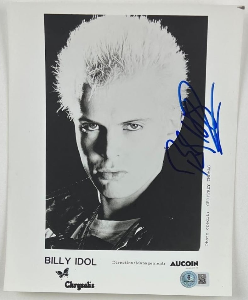 Billy Idol Signed 10" x 8" Press Photo (Beckett Authentication): Black-and-white 10" x 8" press photo signed in blue felt tip marker by musician Billy Idol. In fine condition. Obtained in-person. Authenticated by Beckett, with their official hologram affixed to