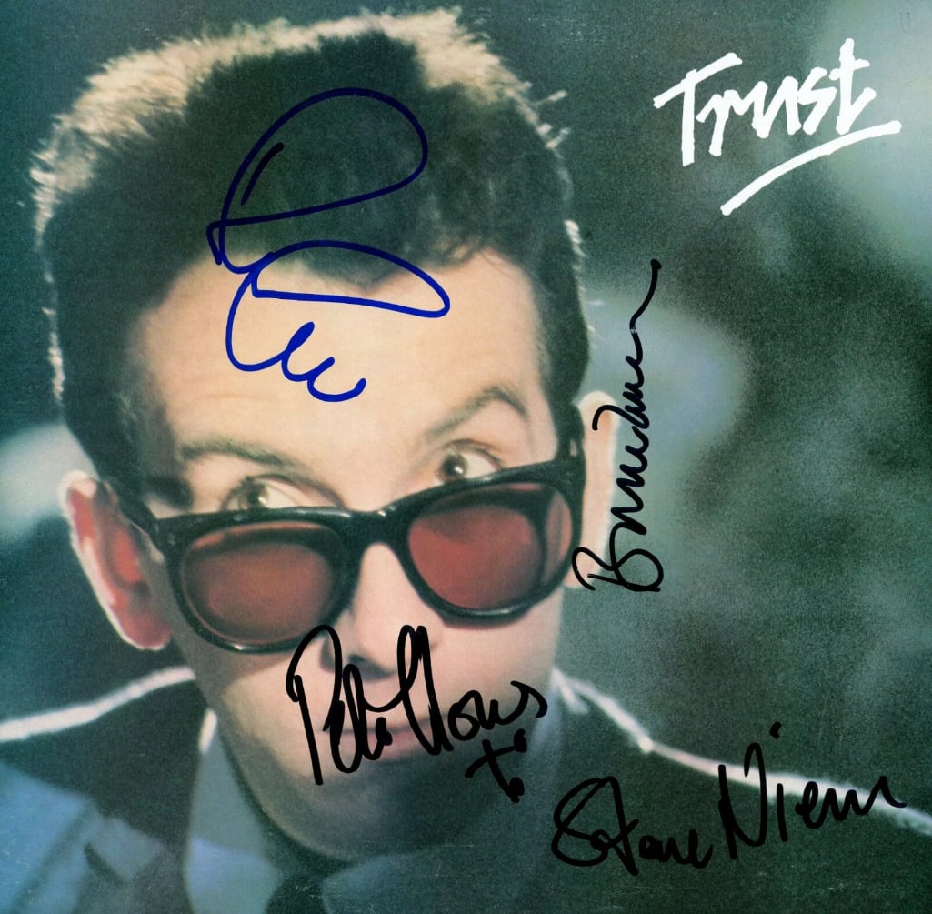 Elvis Costello & the Attractions Fully Group Signed “Trust” LP Album (4 Sigs) (ACOA Auth: “Trust” LP album signed on the cover in blue and black felt tip marker by Elvis Costello and the Attractions backing band members Pete Thomas, Steve Nieve, and Bruce Thomas. Measuring