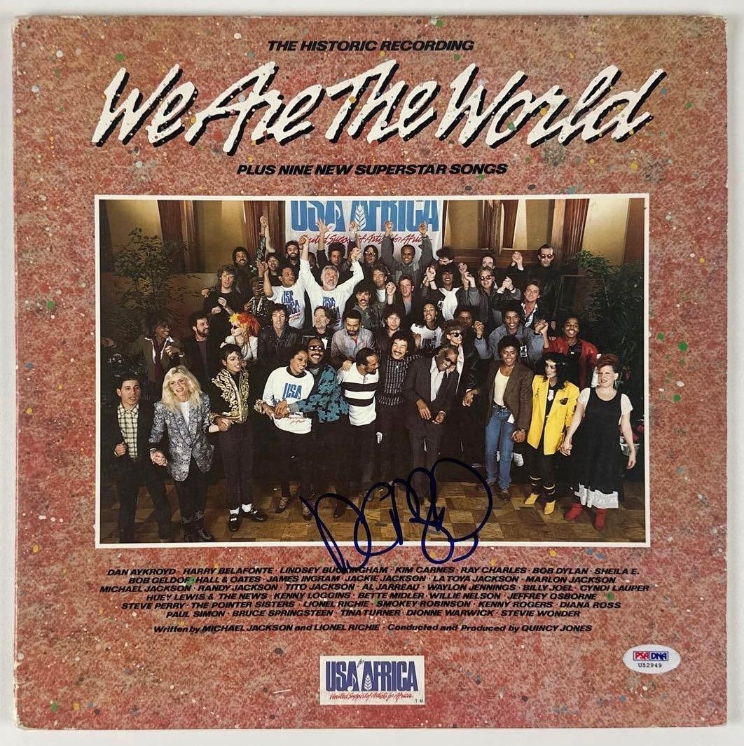 Dan Aykroyd Signed USA for Africa "We Are The World" Album (PSA/DNA Authentication): "We Are The World" album signed on the lower portion of the front cover photo in blue felt tip marker by actor and performer Dan Aykroyd. Measuring approximately 12" x 12" and in good condition with