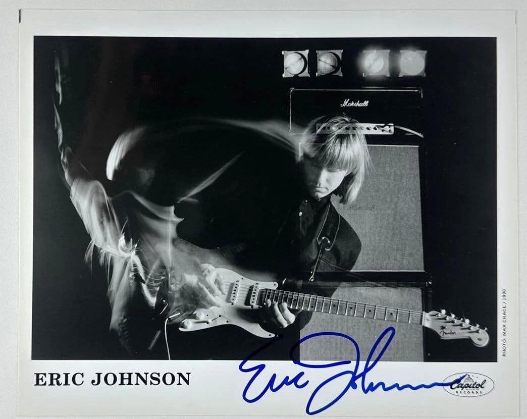 Eric Johnson Signed 8" x 10" Promo Photo (Third Party Guaranteed): Black-and-white 8" x 10" promotional photo signed in blue felt tip marker by musician Eric Johnson. In fine condition. Provenance Eaton & Brennan Auctions guarantees this lot to pass Third-Party