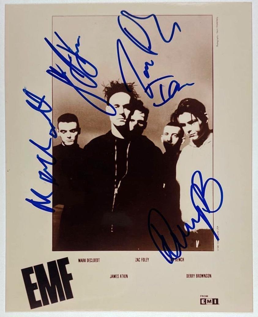 EMF Group Signed 8" x 10" Promo Photo (5 Sigs) (Third Party Guaranteed): Black-and-white 8" x 10" promotional photo signed in blue felt tip marker by EMF band members Ian Dench, Zac Foley, Mark Decloedt, Derry Brownson, and James Atkin. In fine condition. Provenance Eaton