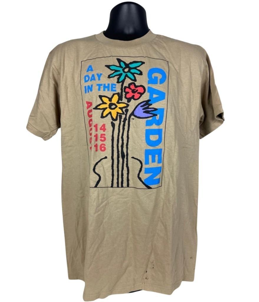 Woodstock 1998 "A Day in the Garden" Concert T-Shirt (Chip Rachlin Collection): Original tan mens size large 30.5" x 19.5" Woodstock 1998 "A Day in the Garden" concert t-shirt. The front features the a black outlined box with the illustration of the neck of a guitar turning into