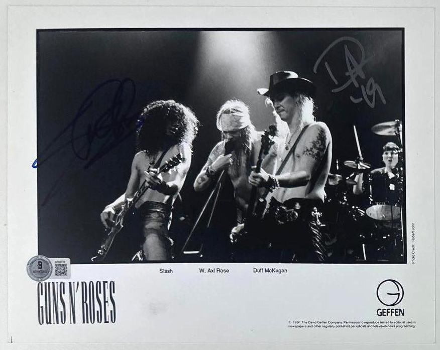 Guns N' Roses: Slash & Duff McKagan Signed 8" x 10" Promo Photo (2 Sigs) (Beckett): Black-and-white 8" x 10" promotional photo signed in silver and blue felt tip markers by Guns N' Roses band members Slash and Duff McKagan. In fine condition. Accompanied by a full Letter of