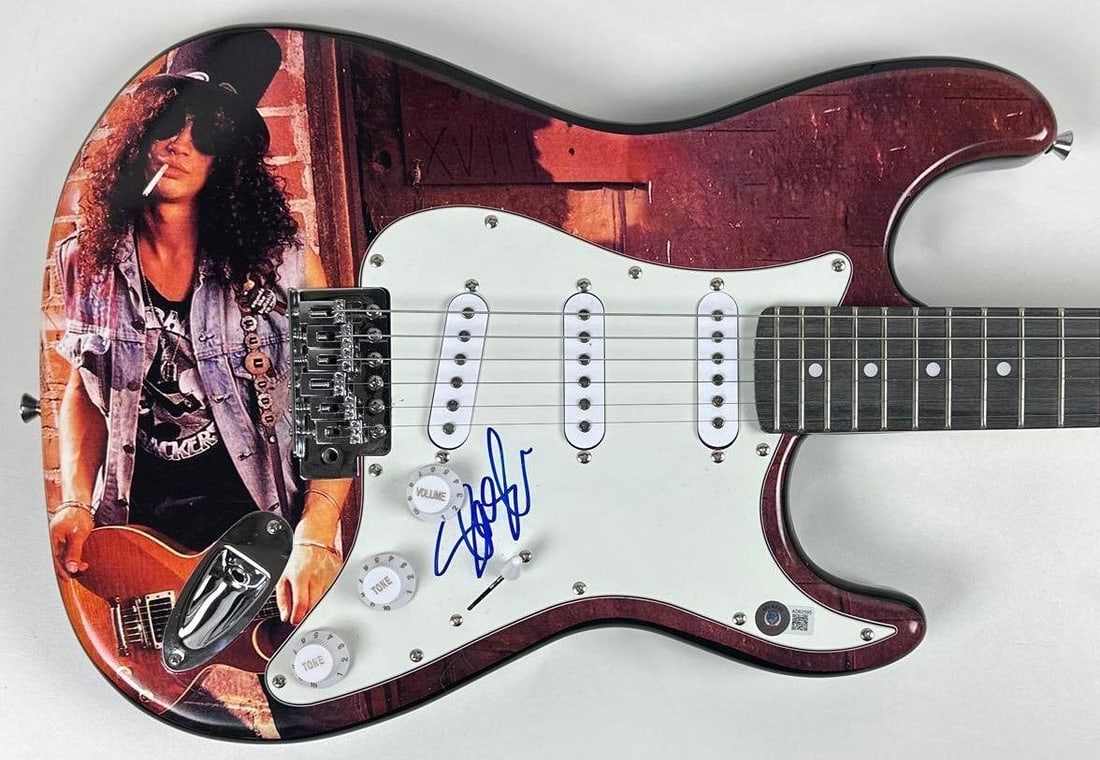 Guns N' Roses: Slash Signed Custom Graphics Stratocaster-Style Guitar (Beckett Authentication): Slash custom graphics Stratocaster-style guitar signed on the pickguard in blue felt tip marker by Guns N' Roses band member Slash. Measuring approximately 39" x 13" and in fine condition.