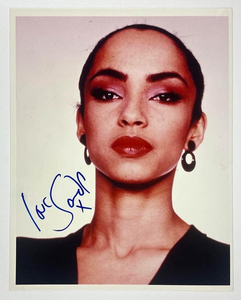 Sade Signed 10" x 8" Photo (JSA Authentication): Color 10" x 8" photo signed in blue felt tip marker by musician Sade. In fine condition. Authenticated by JSA. Provenance This piece was recently authenticated by JSA and may have since had a JSA