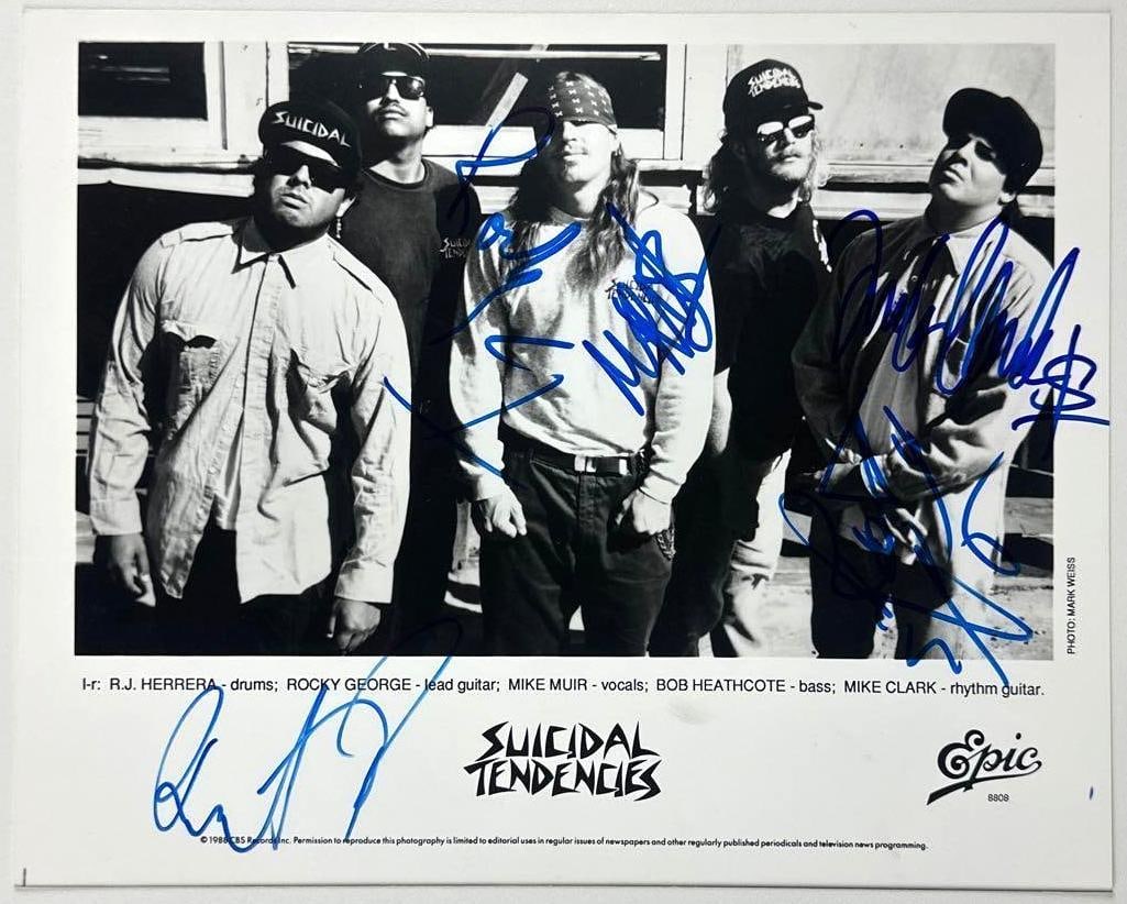 Suicidal Tendencies Group Signed 8" x 10" Promo Photo (5 Sigs) (JSA Authentication): Black-and-white 8" x 10" promotional photo signed in blue felt tip marker by Suicidal Tendencies band members R. J. Herrara, Rocky George, Mike Muir, Bob Heathcote, and Mike Clark. In fine condition. 