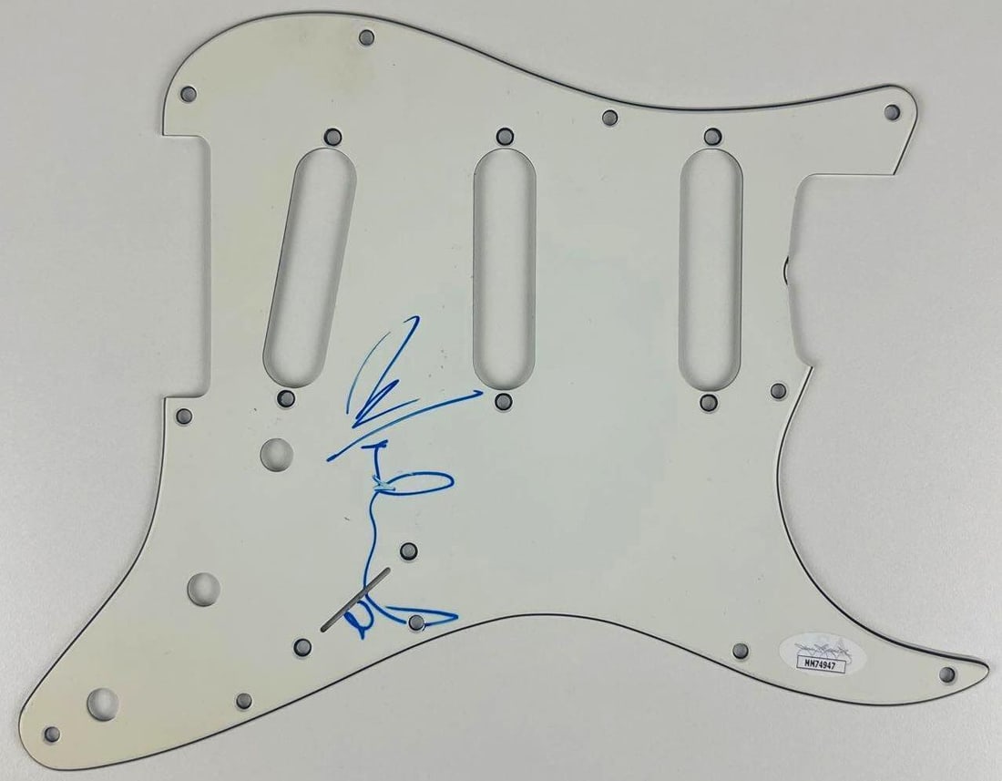 A-ha: Martin Harket Signed Stratocaster-Style Pickguard (JSA Authentication): White 9" x 11" Stratocaster-style pickguard signed on the front in blue felt tip marker by A-ha band member Martin Harket. In fine condition. Accompanied by a JSA COA (#MM74947).