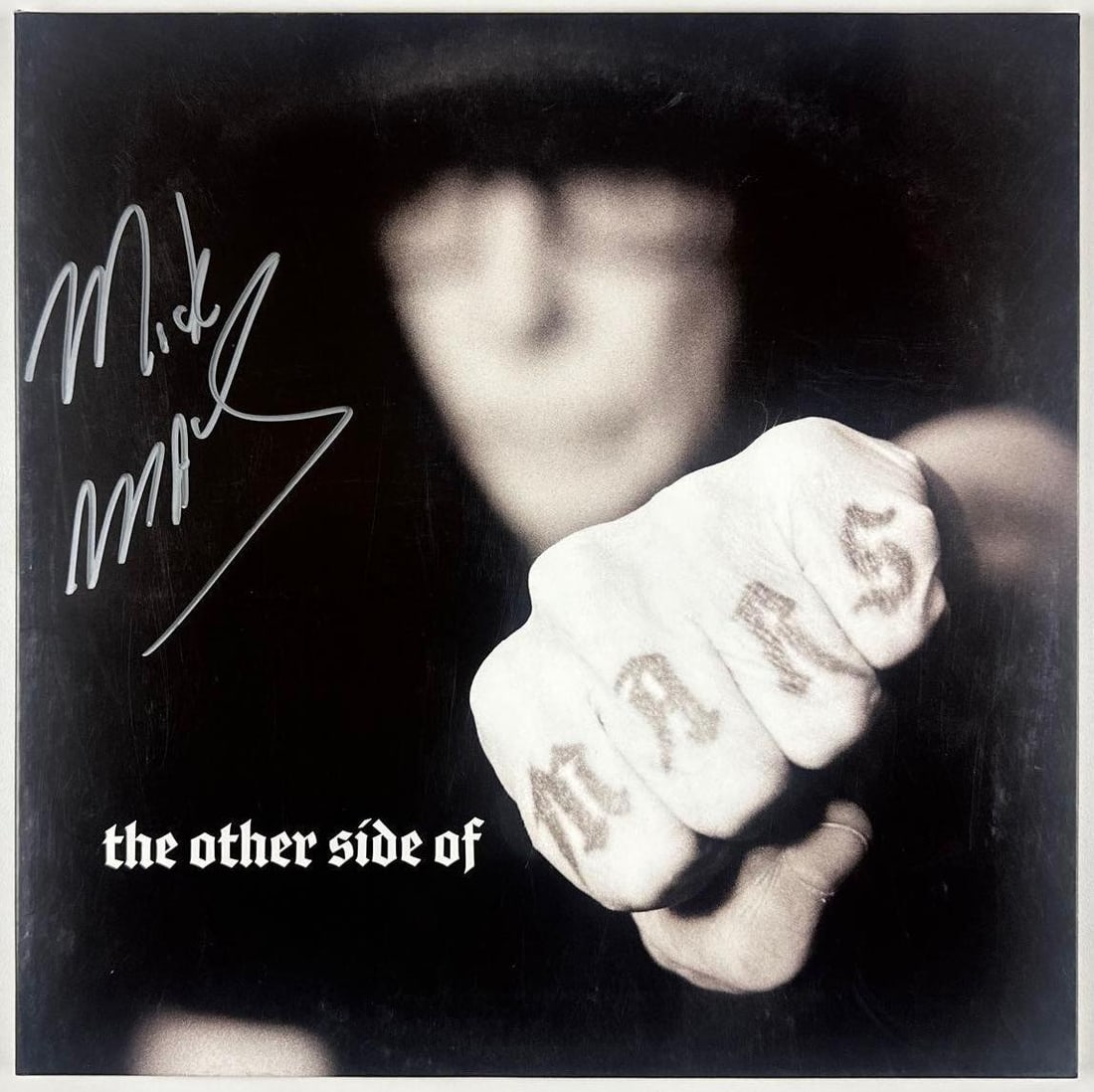 Motley Crue: Mick Mars Signed "The Other Side of Mars" Album (Beckett): "The Other Side of Mars" album signed on the cover in silver marker by Motley Crue guitarist Mick Mars. Measuring approximately 12" x 12" and in good condition with minor handling wear along the edges