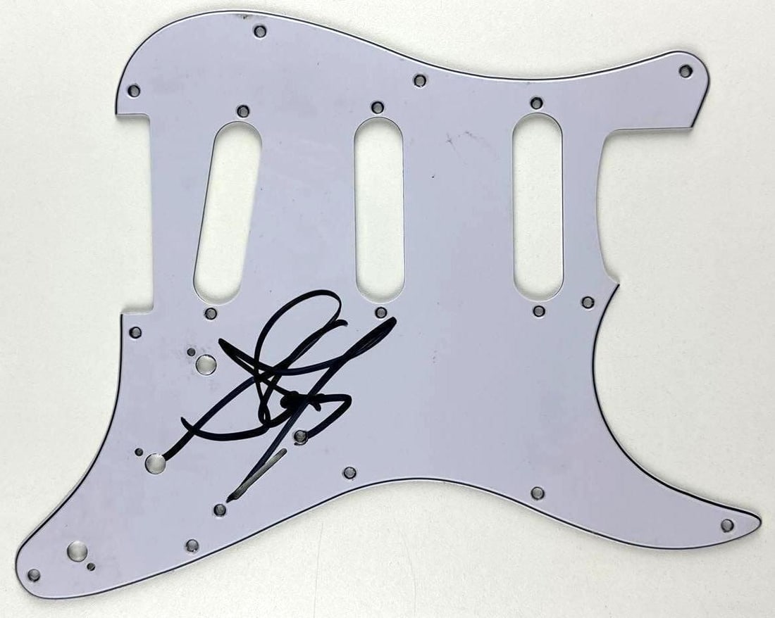 Aerosmith: Steven Tyler Signed Stratocaster-Style Pickguard (Third Party Guaranteed): White 10.75" x 8.75" Stratocaster-style pickguard signed in black felt tip marker by Aerosmith band member Steven Tyler. In fine condition. Provenance Eaton & Brennan Auctions guarantees this lot to