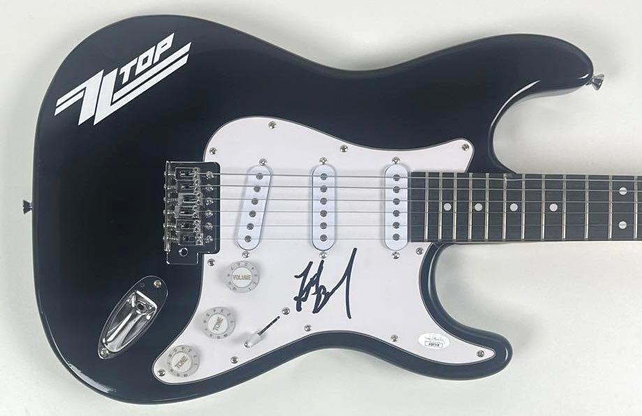 ZZ Top: Frank Beard Signed Stratocaster-Style Guitar (JSA Authentication): Black Stratocaster-style guitar with ZZ Top logo signed on the pickguard in black felt tip marker by ZZ Top band member Frank Beard. Measuring approximately 39" x 12.75" and in fine condition.